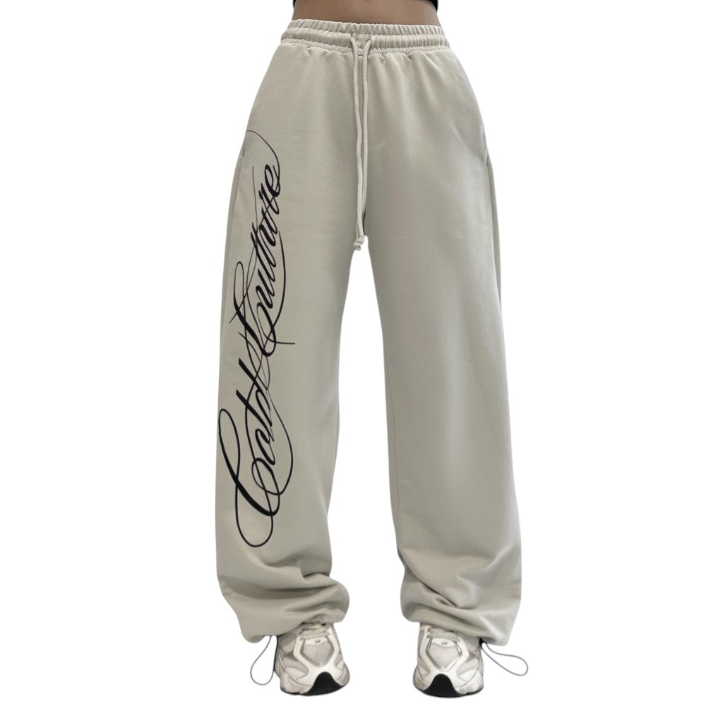 SWAGTOK light beige polyester baggy Y2K sweatpants with black script logo and drawstring waist.