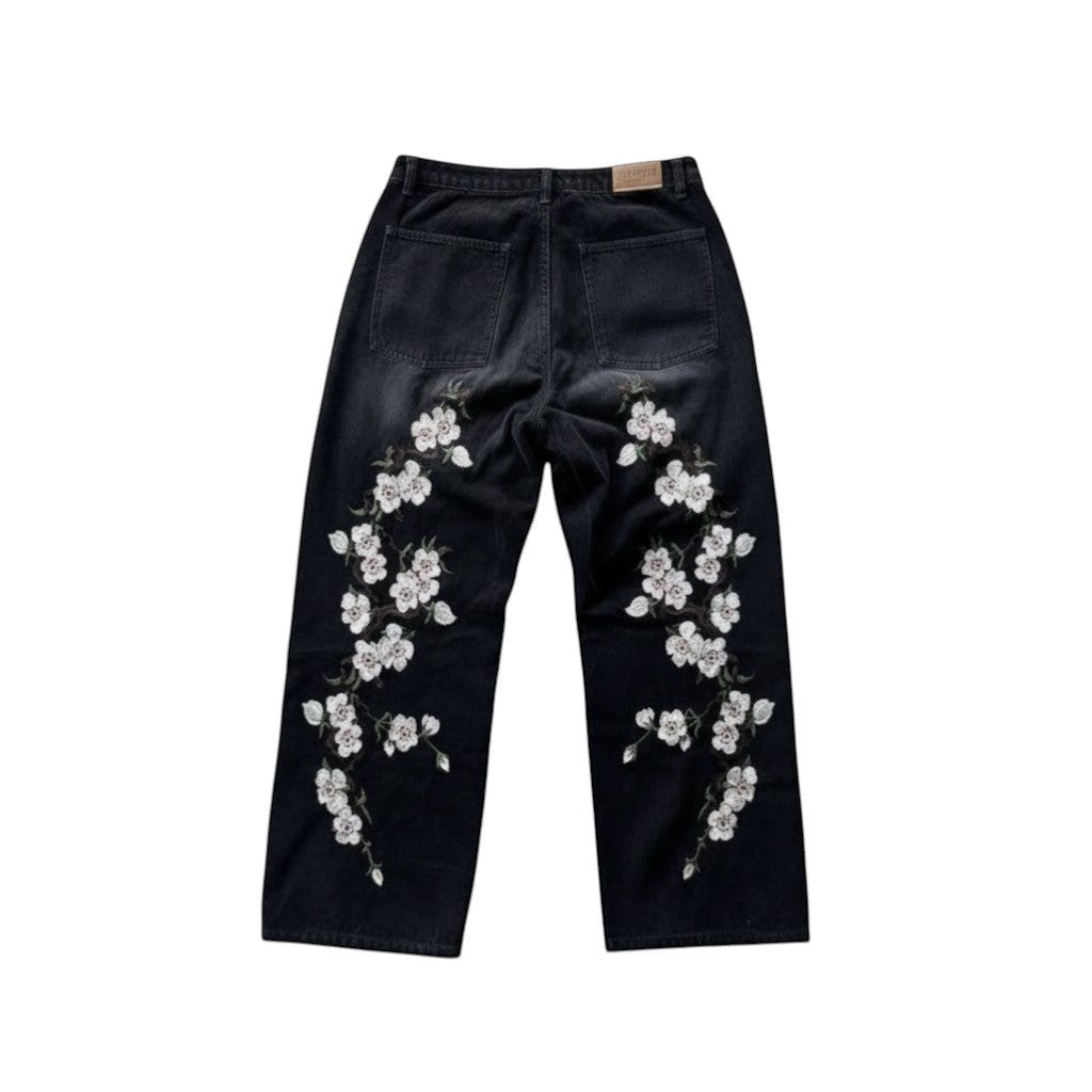 SWAGTOK black denim straight-leg trousers with embroidered white flowers on legs. Casual summer style.
