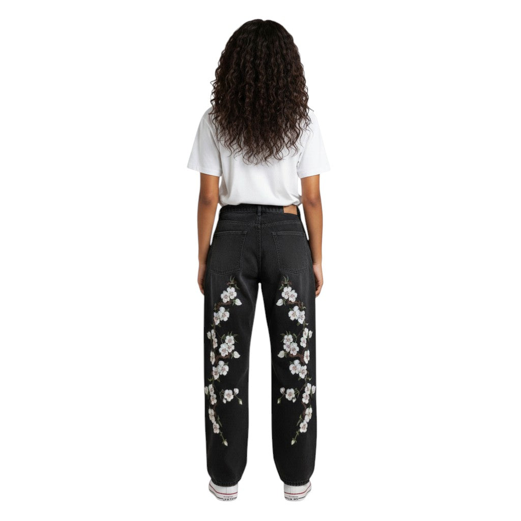 SWAGTOK black denim straight-leg jeans with embroidered white cherry blossoms on the legs. Mid-waist, zip fly.