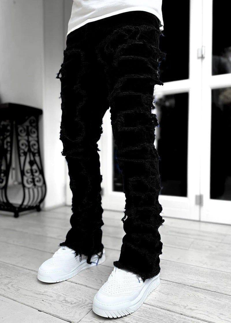 SWAGTOK black cotton stacked jeans with distressed ripped detailing and frayed hems.