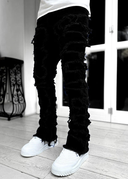 SWAGTOK black cotton stacked jeans with distressed ripped detailing and frayed hems.