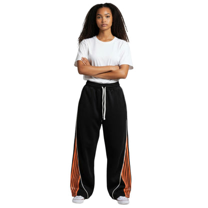 SWAGTOK black polyester loose-fit track pants with orange and white striped side panels and white drawstring.