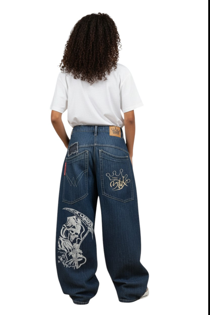 SWAGTOK blue denim loose fit jeans with skull and crown graphic prints, featuring a baggy style.