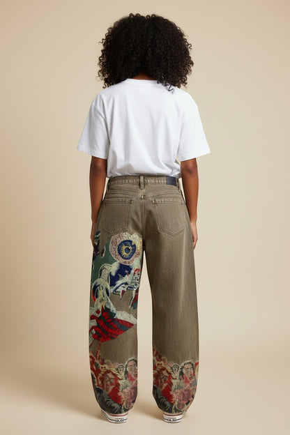 SWAGTOK brown cotton straight leg jeans with graphic tapestry print on legs featuring screaming faces and mythical creatures.