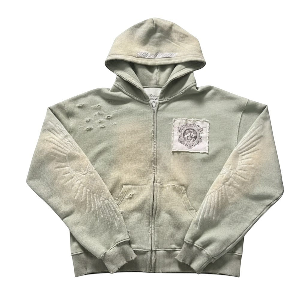SWAGTOK light green distressed zip-up hoodie with embroidered wings and a decorative patch on the chest.