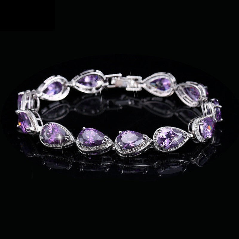 SWAGTOK platinum plated bracelet with purple drop-shaped zircon stones and small clear accent stones.