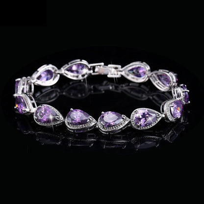 SWAGTOK platinum plated bracelet with purple drop-shaped zircon stones and small clear accent stones.